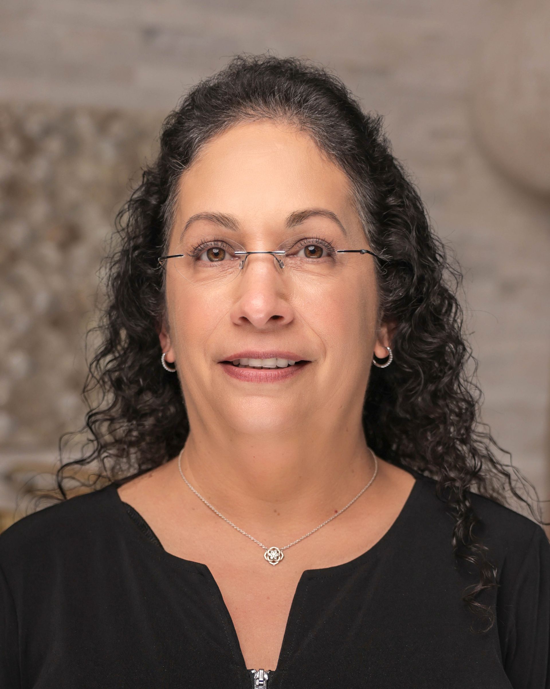 A woman wearing glasses and a black shirt is smiling for the camera.