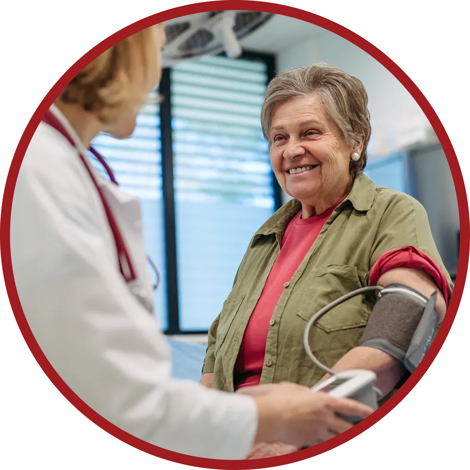 Doctor taking an older woman's blood pressure in a medical office. Woman smiles.