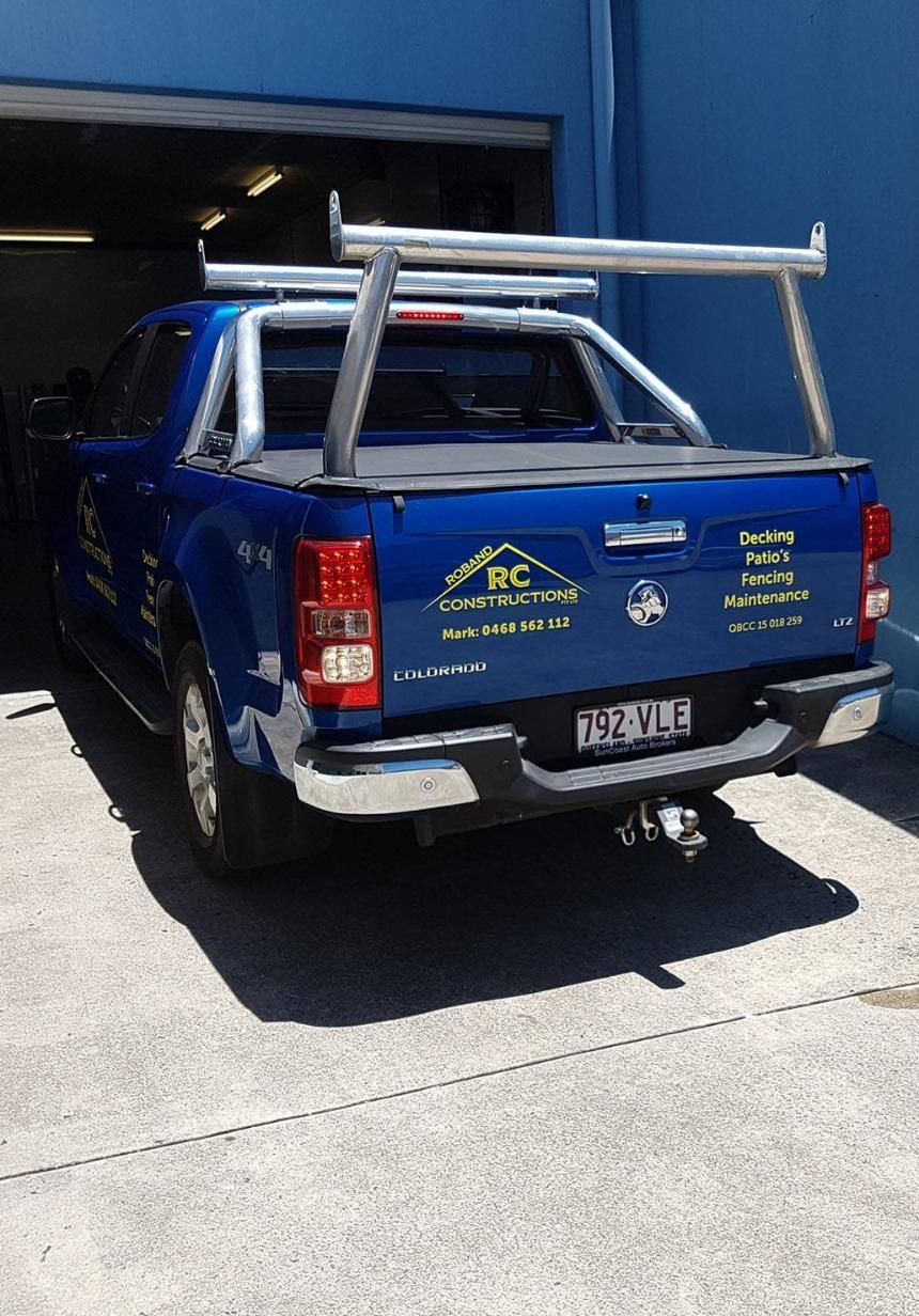 A Blue Truck With a Ladder Rack on the Back is Parked in Front of a Blue Building — Caledonian Colour In Kunda Park, QLD