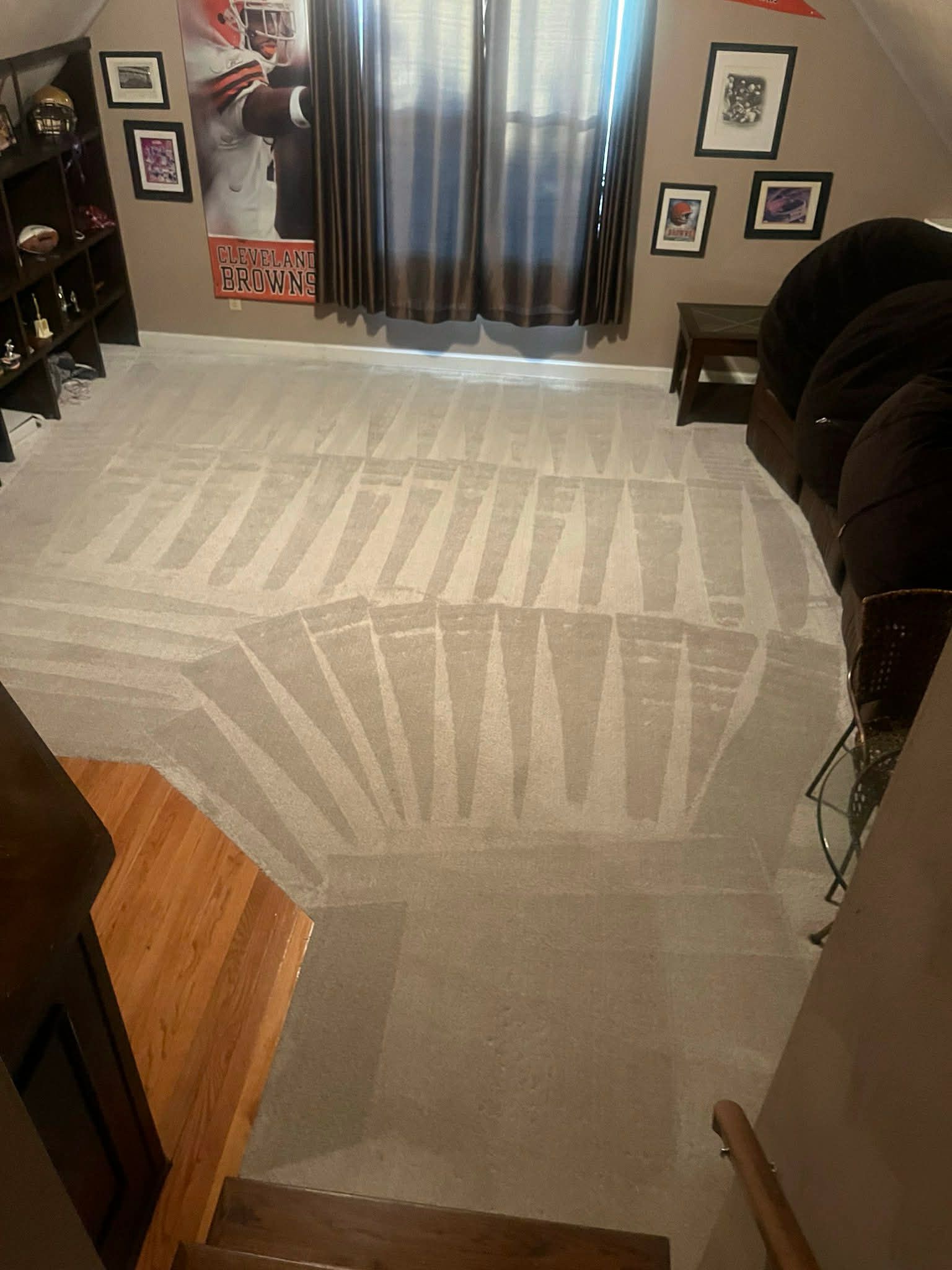 Person in green pants vacuums a white patterned rug in a living room. Yellow vacuum cleaner visible.