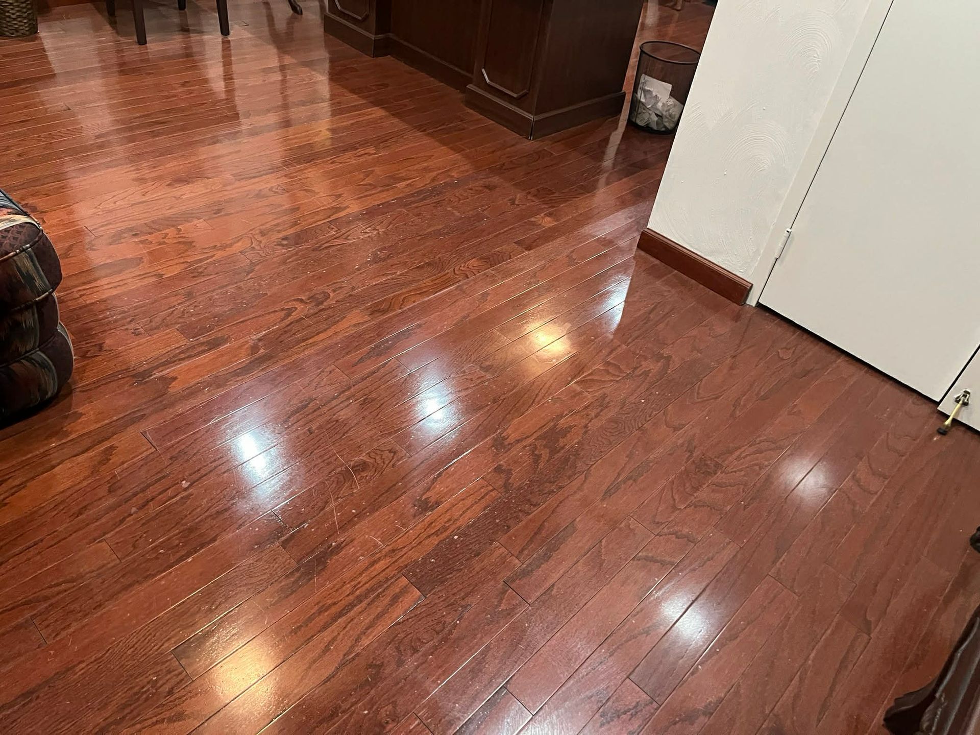 Person using a floor buffer to clean a shiny, reflective floor in an office building.