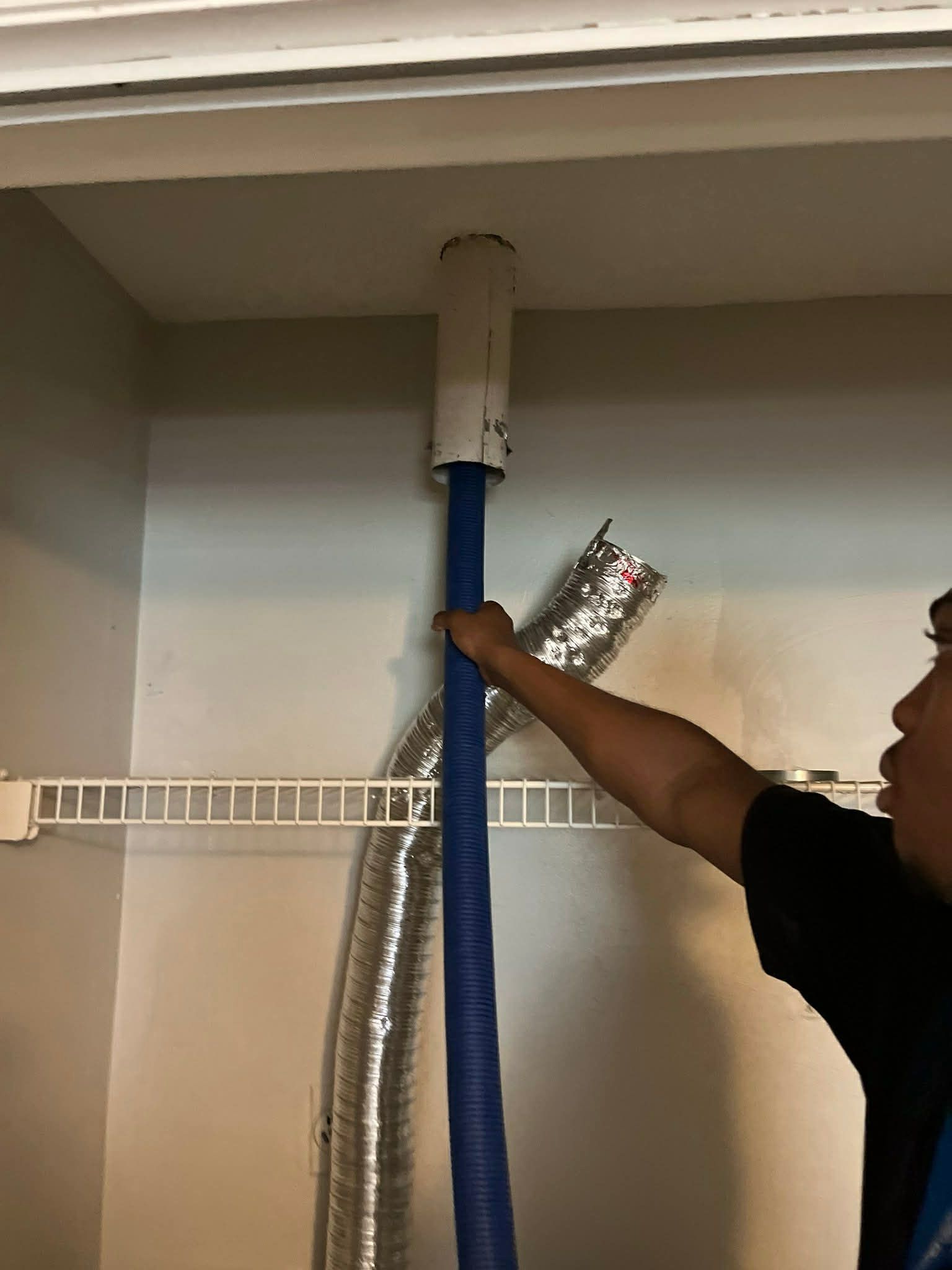 Construction worker in hard hat and overalls working on ceiling framework.