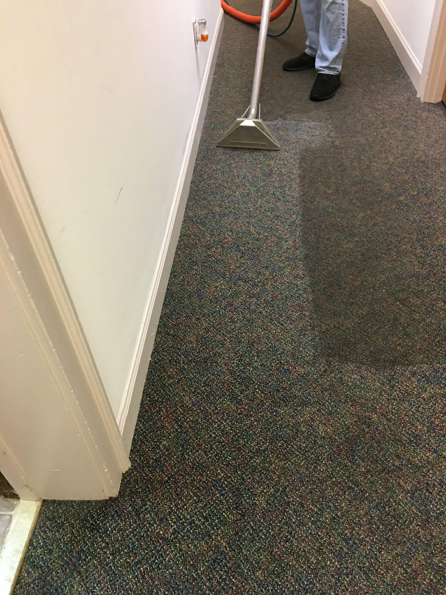White pipes connected to a radiator on a beige-colored laminate floor, with a small water leak visible.