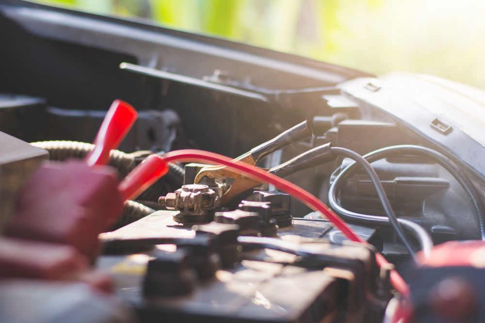 Car Battery With Red Jumper Cable Connected — Jims Auto Care in Berrimah, NT