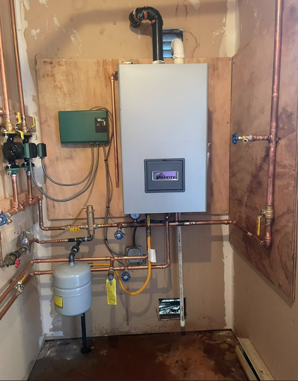 A room with a boiler and copper pipes on the wall