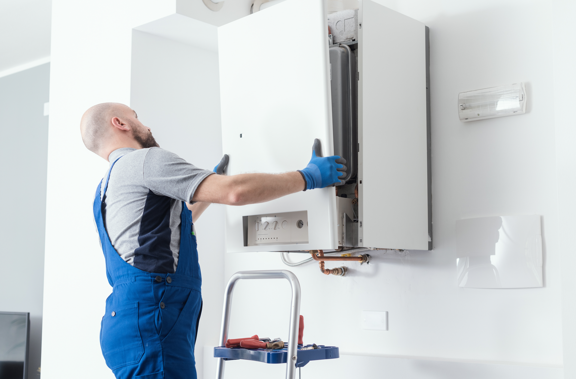A man is installing a boiler on a wall.