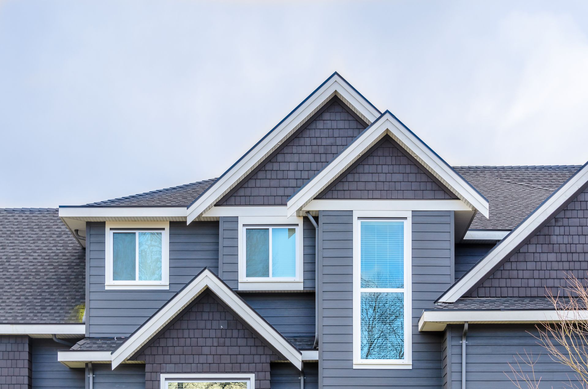 A large gray house with a roof and a lot of windows.