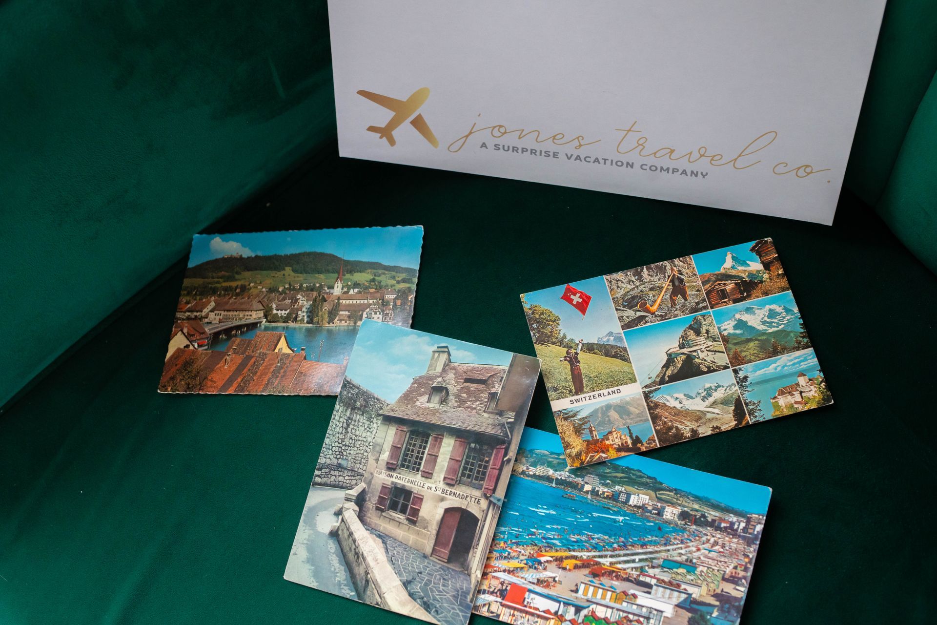 Four postcards are sitting on a green couch in front of a sign that says ' yourtravel.com '
