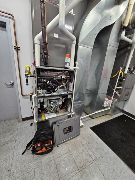 Furnace with open panels and tools nearby; in a utility room with ductwork.