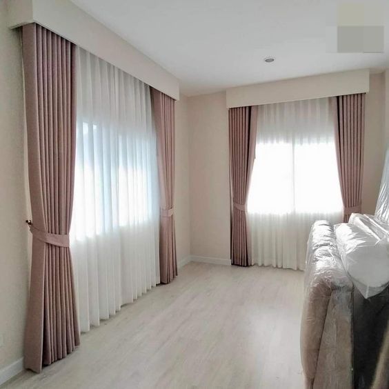 Hay dos ventanas en la habitación con cortinas.