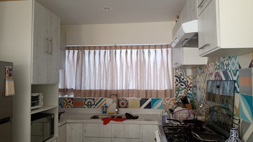 Una cocina con gabinetes blancos, una estufa, un fregadero y una ventana.