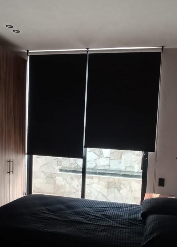 Un dormitorio con una cama y una ventana con persianas negras.