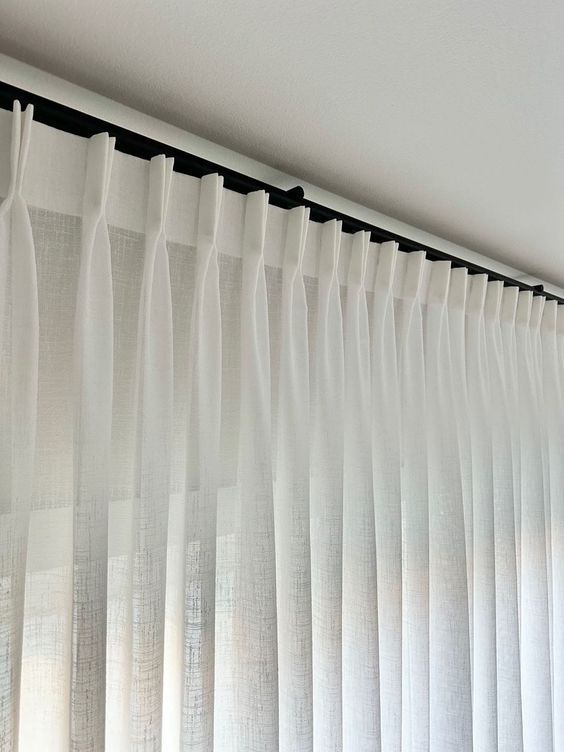 Un primer plano de un par de cortinas blancas en una ventana.