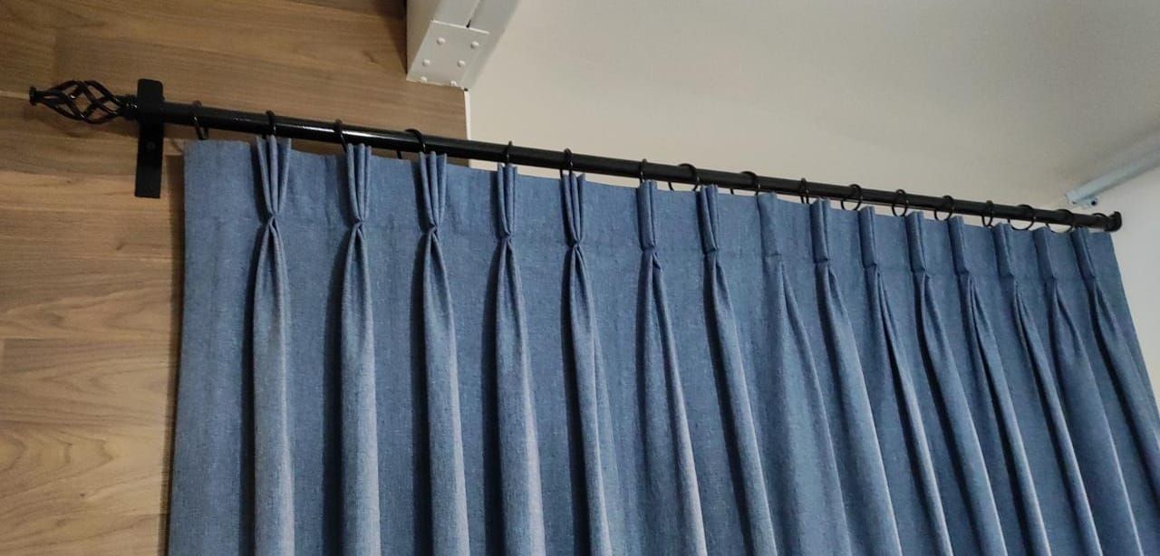 Un primer plano de una cortina azul con una barra de cortina negra.