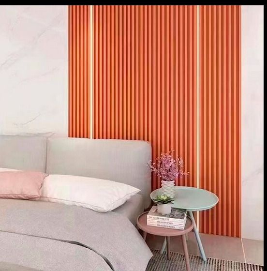 Un dormitorio con cama, mesa y pared rayada.