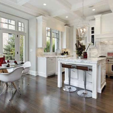 Una cocina con muebles blancos, taburetes, una mesa y sillas.