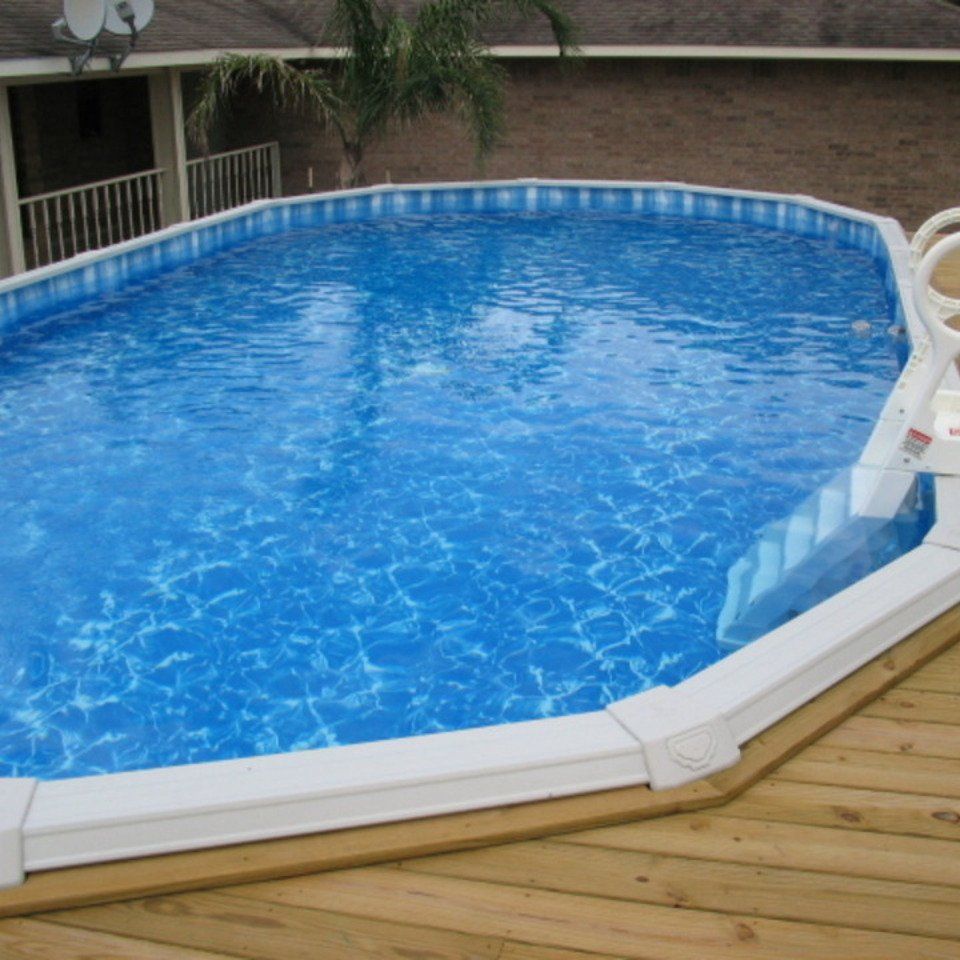 A large swimming pool is sitting on a wooden deck