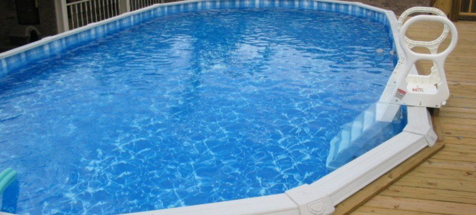 A large swimming pool is sitting on top of a wooden deck.