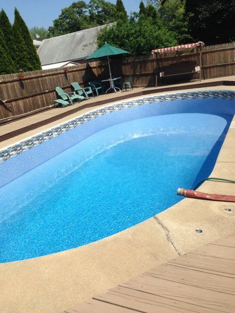A large swimming pool with a wooden fence in the background