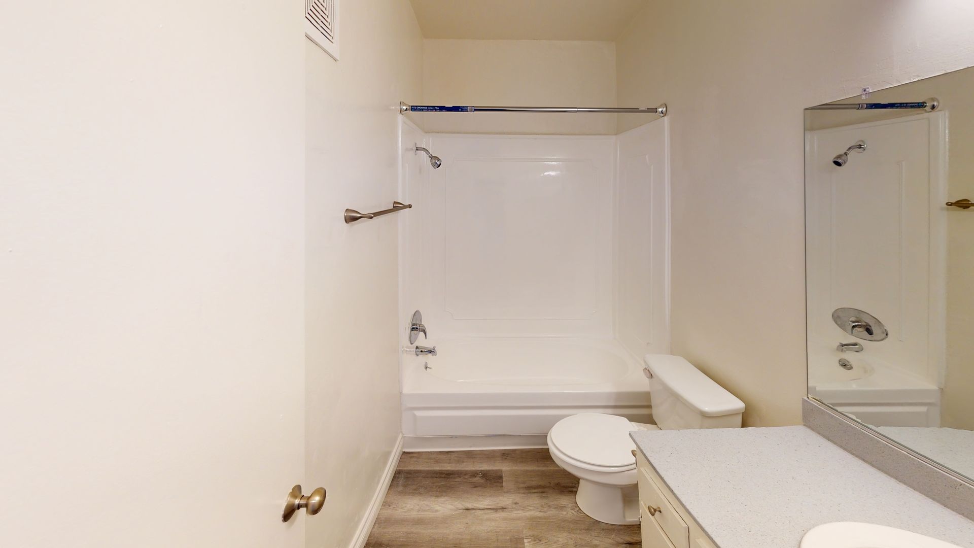 Bathroom with a white shower and toilet, neutral walls, and a light-colored countertop.