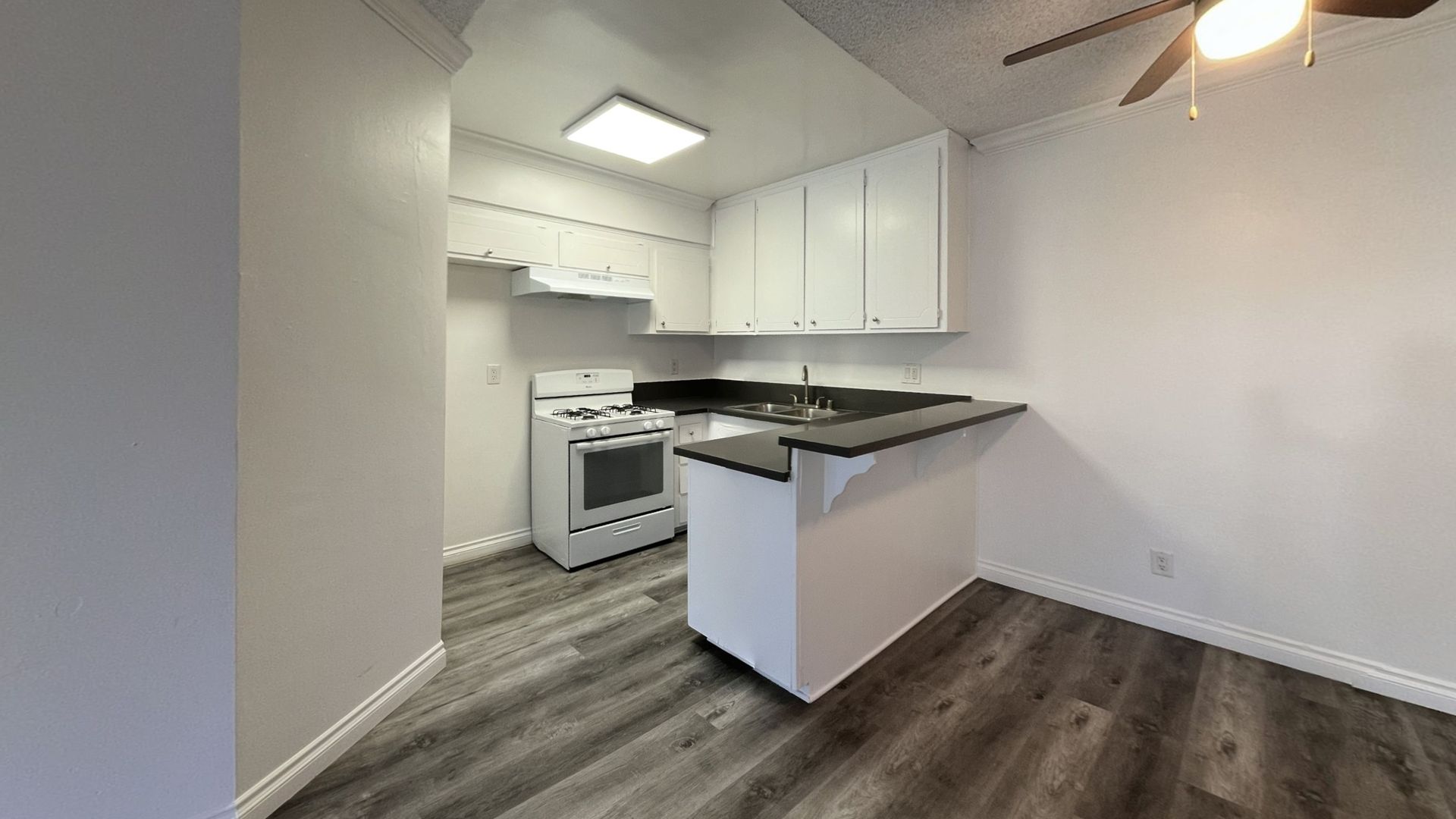 Small kitchen with white cabinets, dark countertops, and gray flooring.