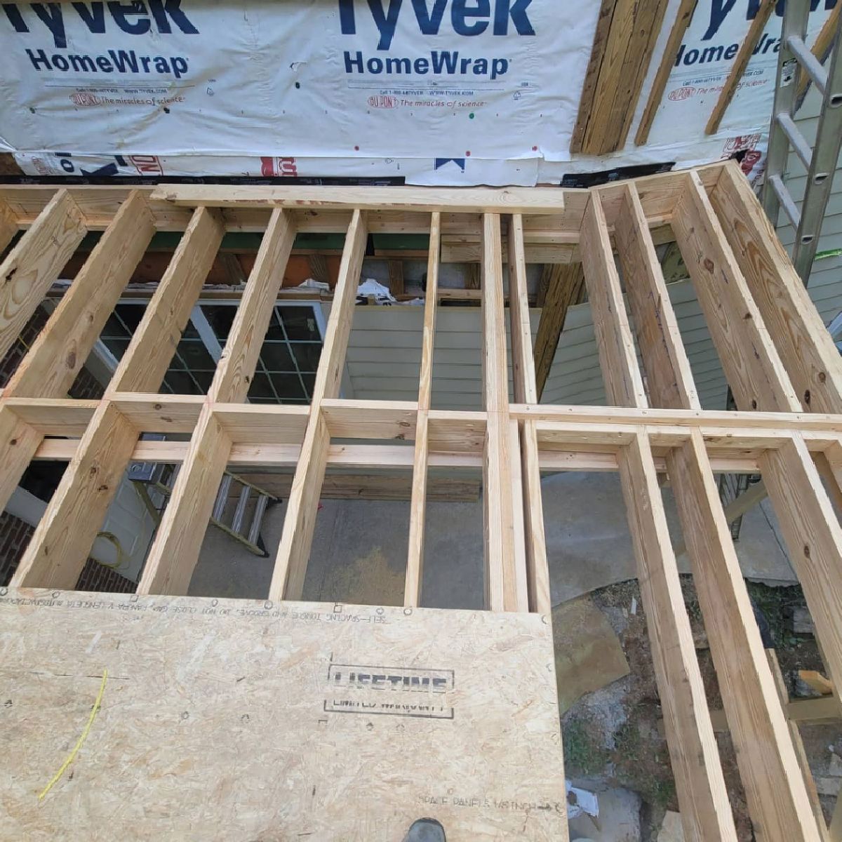 Wooden frame construction, possibly a wall, with plywood base and Tyvek wrap overhead.