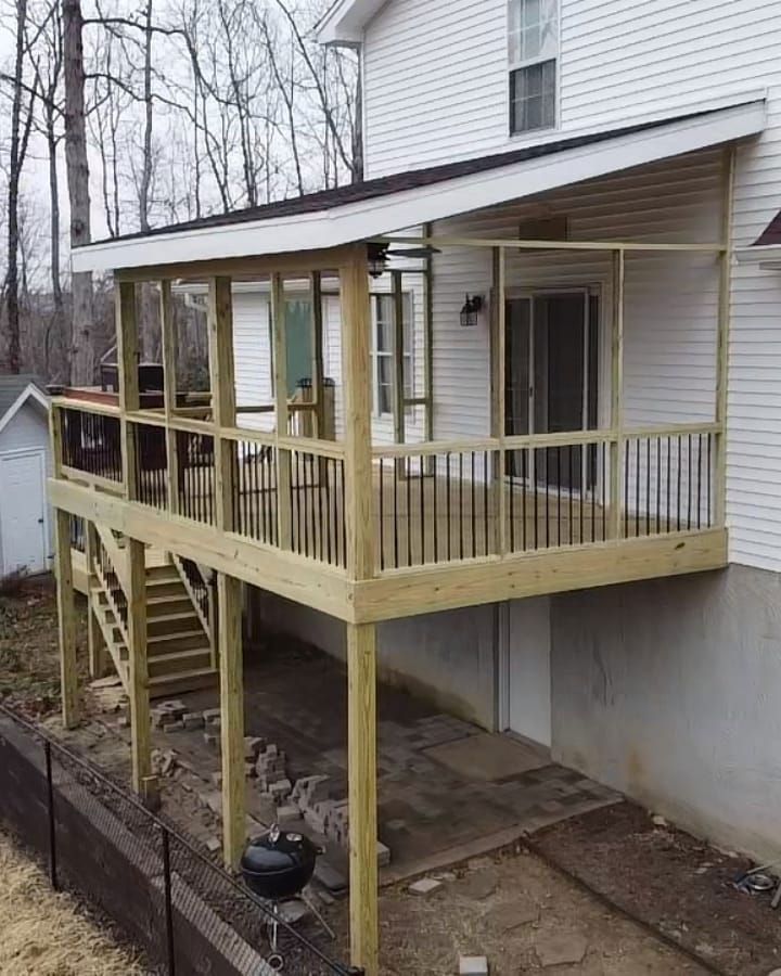 Wooden deck and screened porch attached to a white house, with stairs and an outdoor grill.
