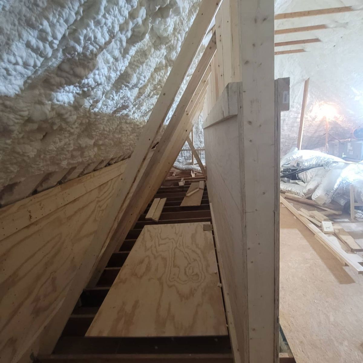 Interior attic construction with wood framing, insulation, and plywood flooring.