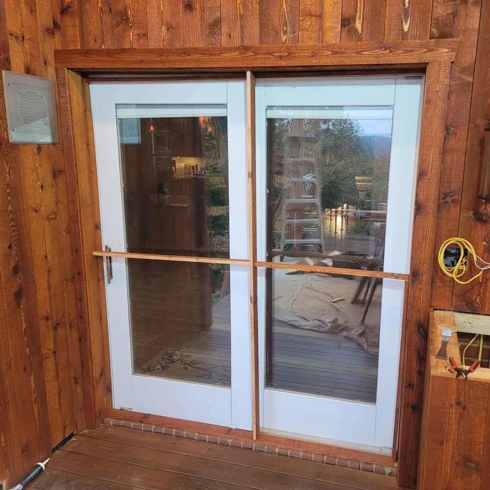 Wooden framed double glass doors; interior, light brown wood; makeshift bar across door.
