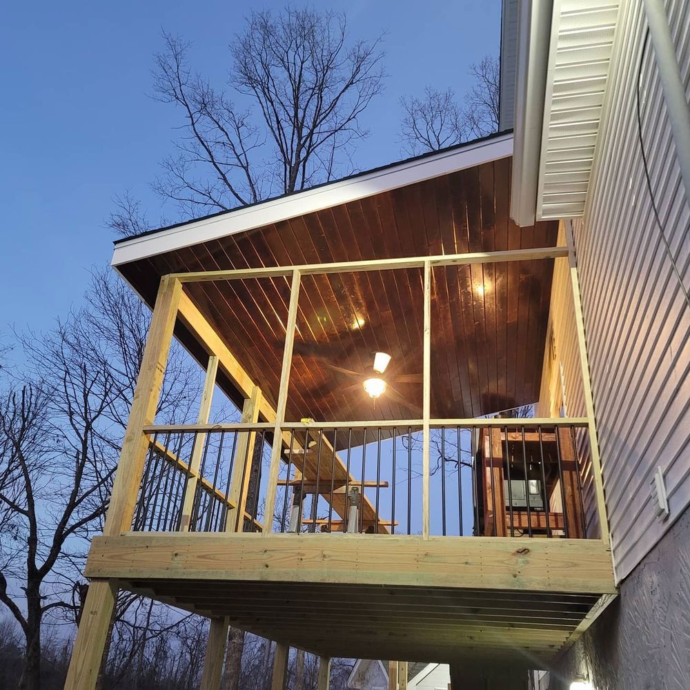 Wooden screened-in porch with ceiling lights, attached to a house. Sky is visible.