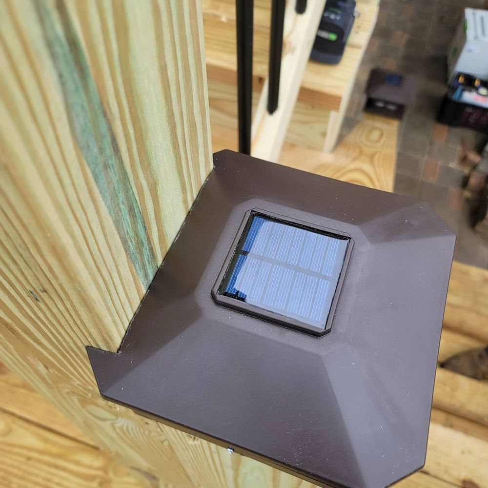 Solar-powered brown light attached to wooden steps with black railing in the background.