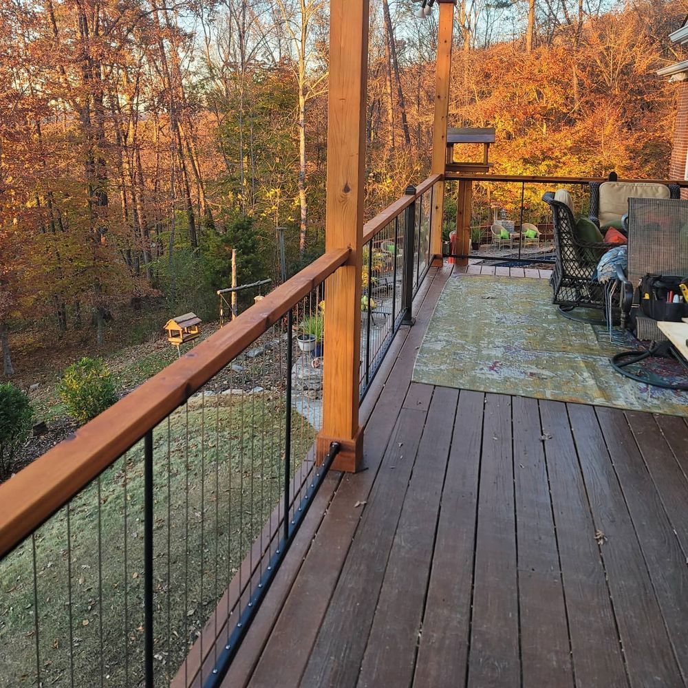 Wooden deck with black cable railings overlooking autumn woods.