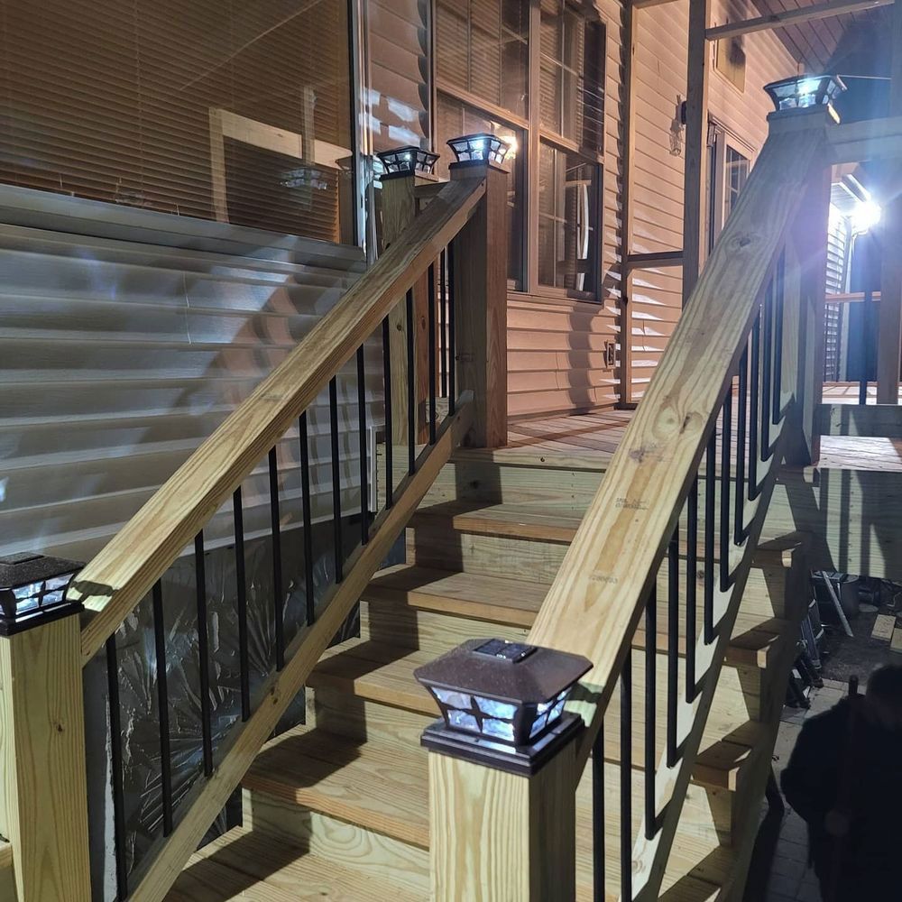 Wooden staircase with solar lights on the posts leading up to a house at night.