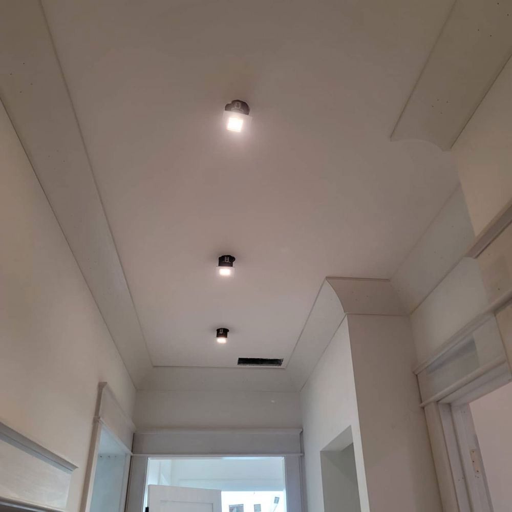 Ceiling of hallway with three spotlights, white walls, and molding.
