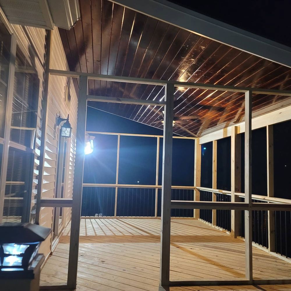 Screened-in porch under construction at night; wooden frame and ceiling, deck, dark sky.