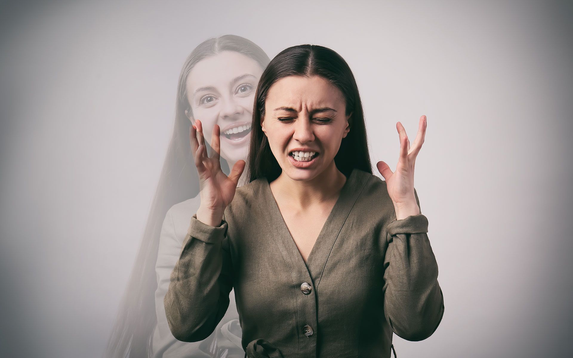 Woman with angry face and raised hands; blurred image of smiling woman behind.