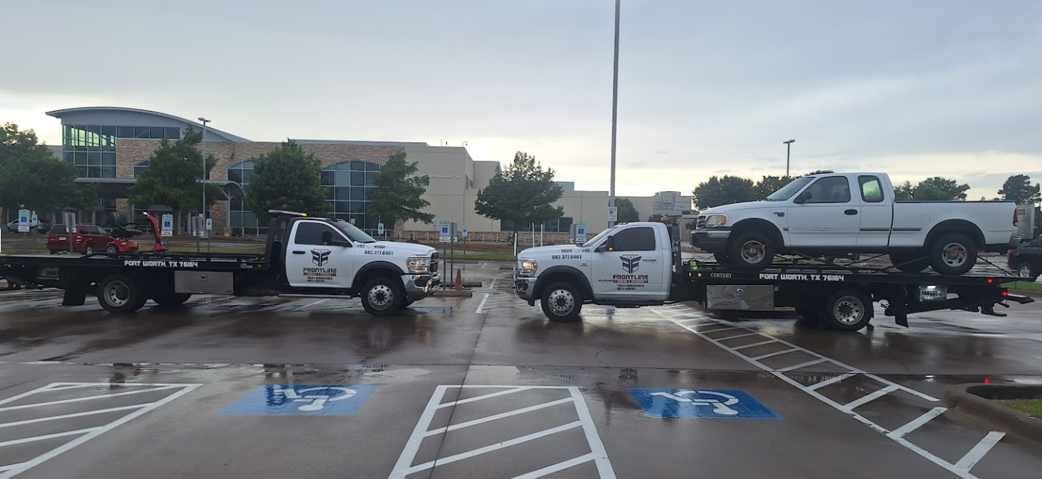 Three tow trucks are parked in a parking lot.