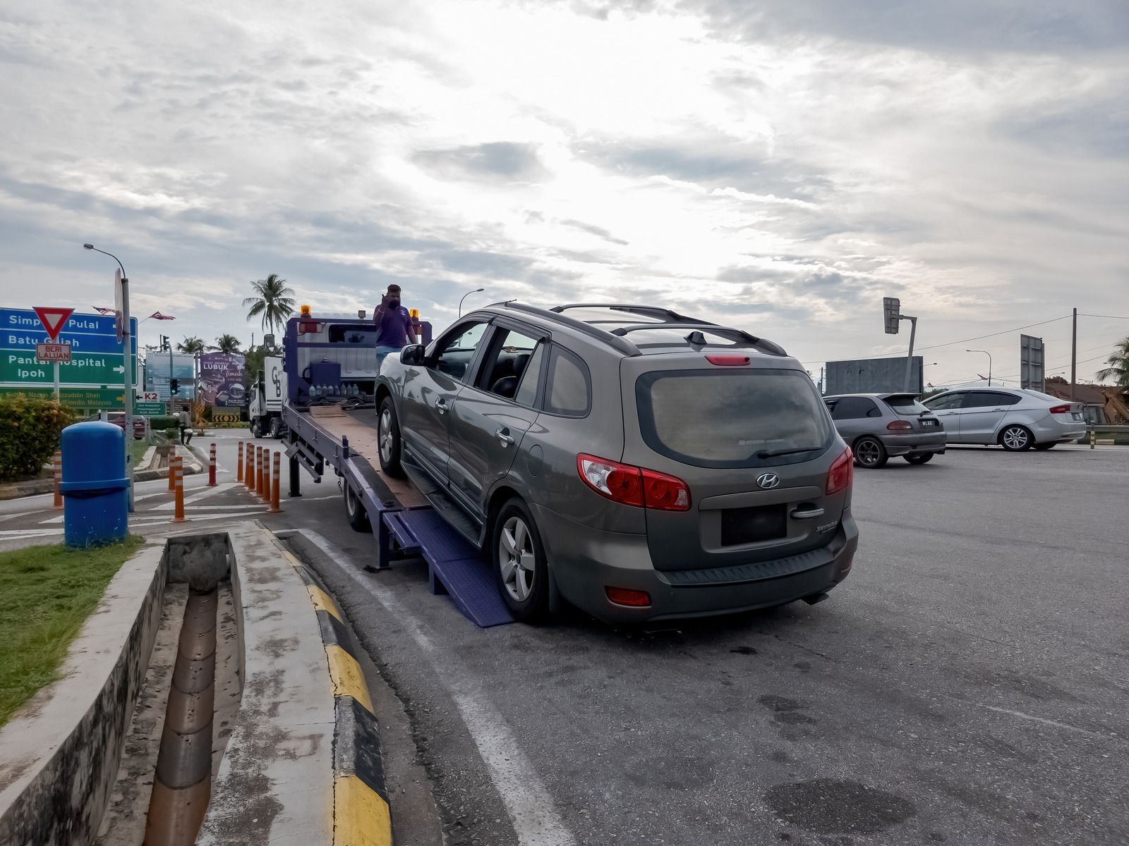 A car is being towed by a tow truck in a parking lot.