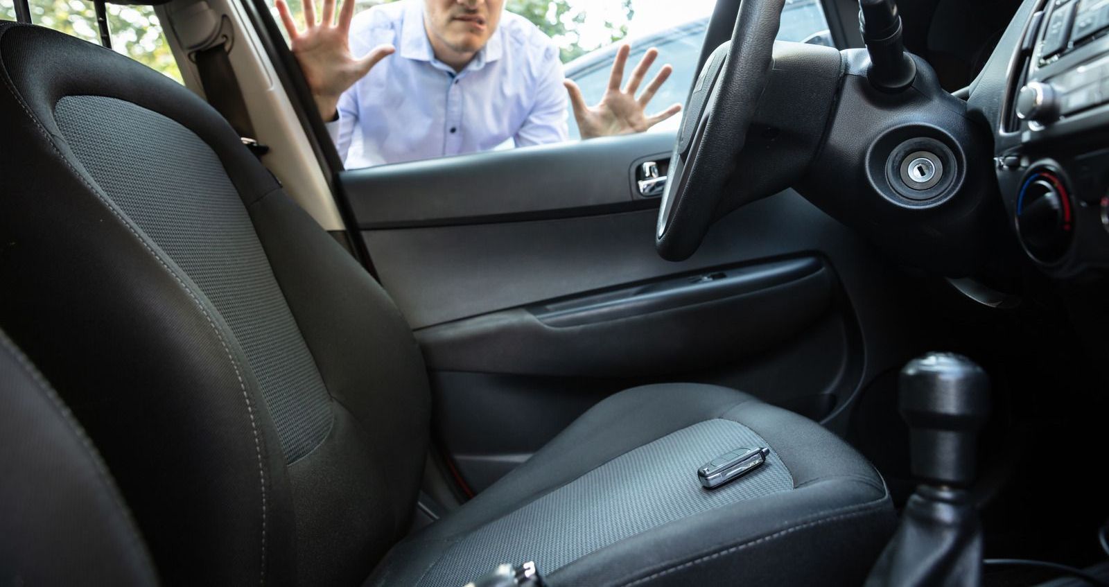 A man is looking through the window of a car.