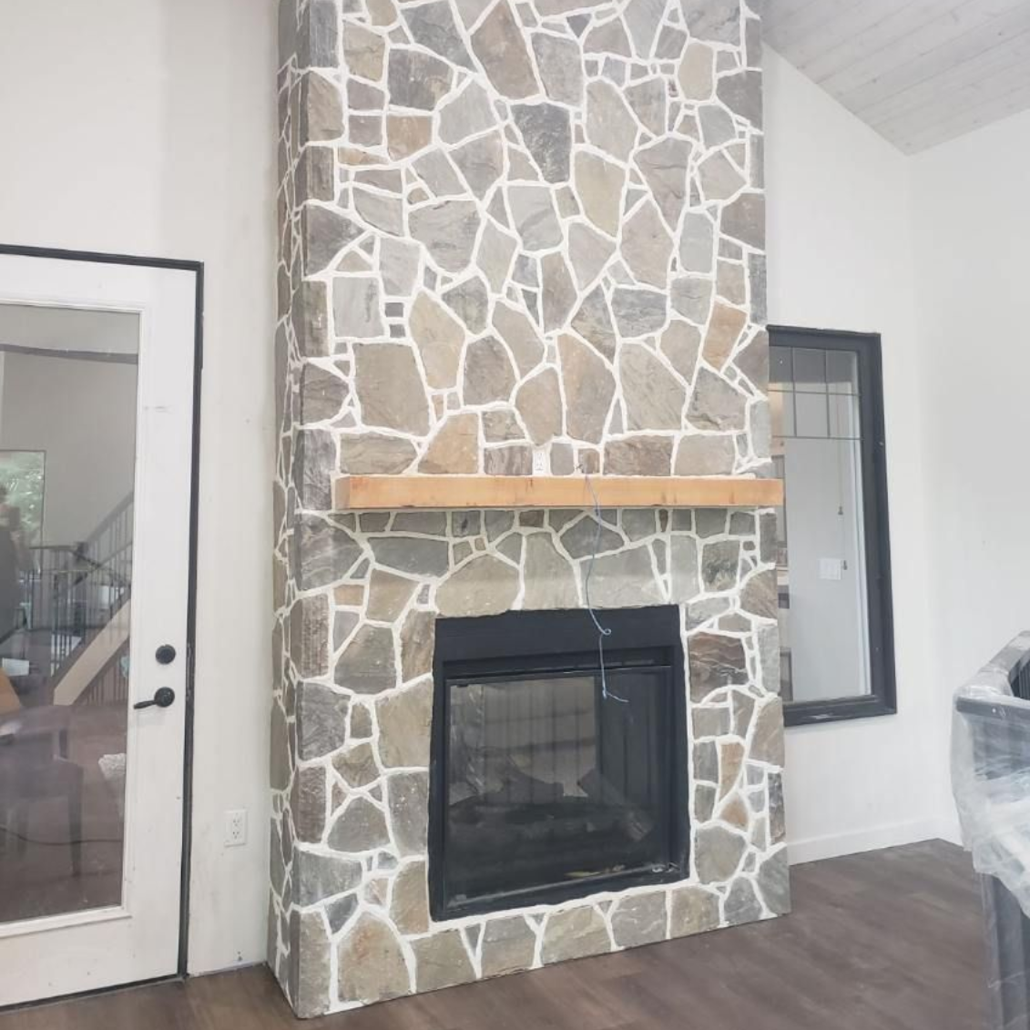 Stone fireplace in a bright room with tile flooring.