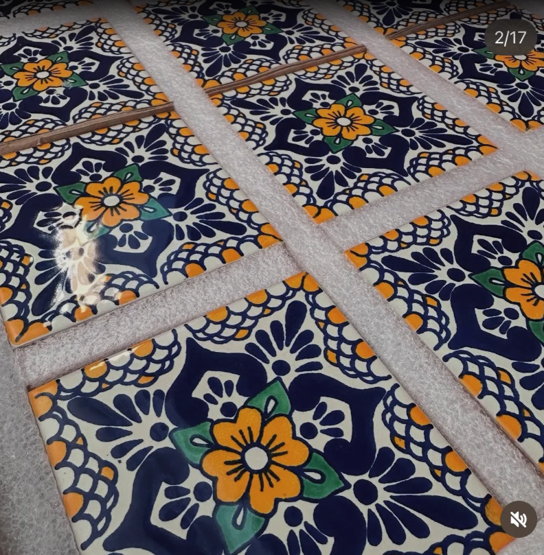 Brick wall with arched doorway leading to a patio with a red pot and a ladder.