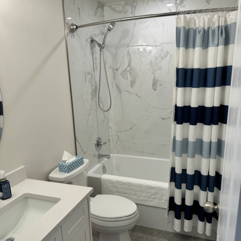 Brick wall with arched doorway leading to a patio with a red pot and a ladder.