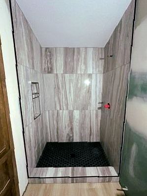 A bathroom with a walk in shower and tiled walls.