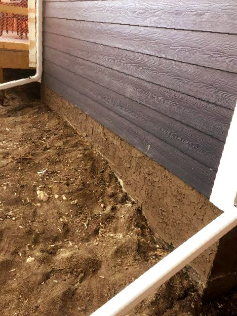 A house with a blue siding and a white pipe in the dirt