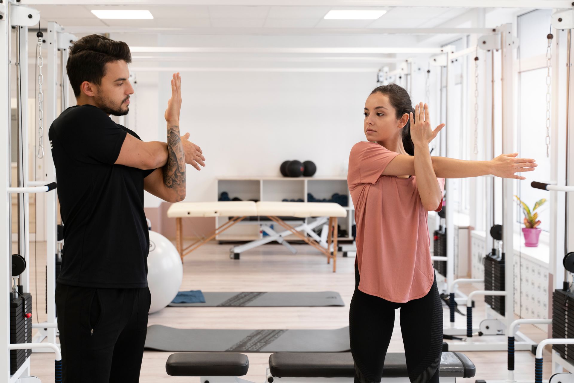a man and a woman are stretching their arms in a gym .