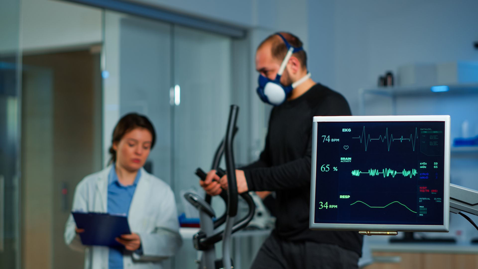 a man is wearing a mask while riding an exercise bike in a lab .