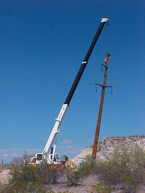 Utility Pole being placed in hole by a crane