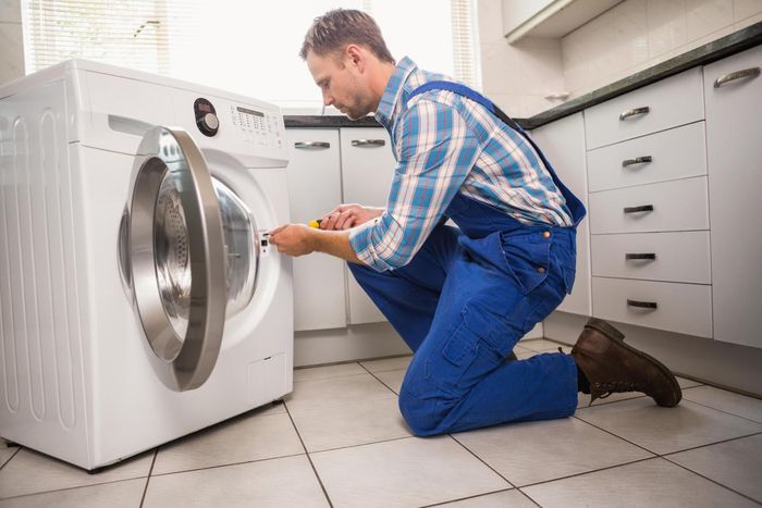 man kneeling while fixing the dryer