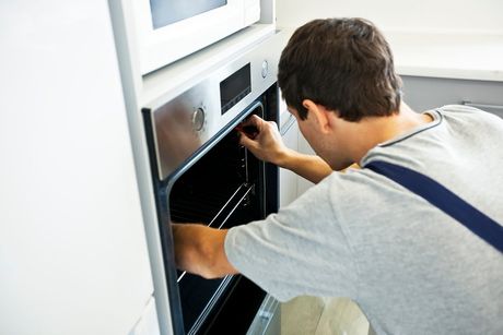 man fixing an oven