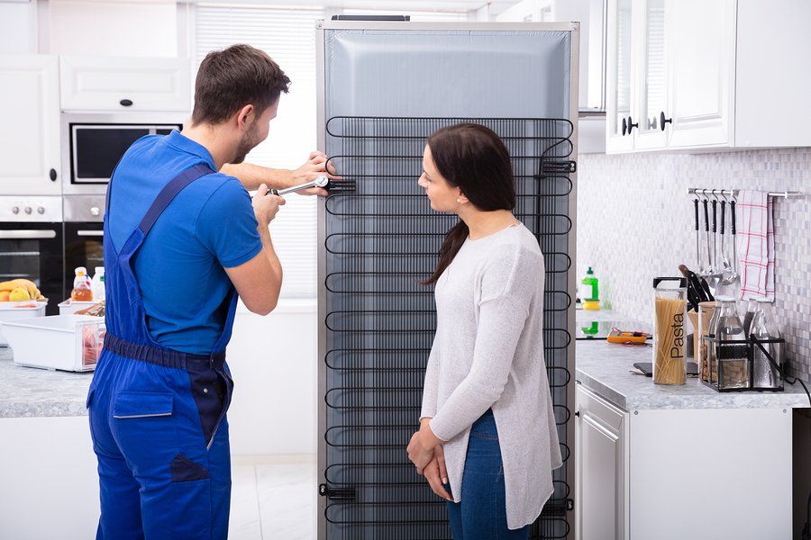 man fixing the refrigerator while a customer watches